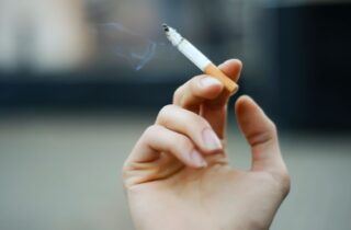 closeup image of a hand holding a lit cigarette oral health smoking effects dentist in Strongsville Ohio